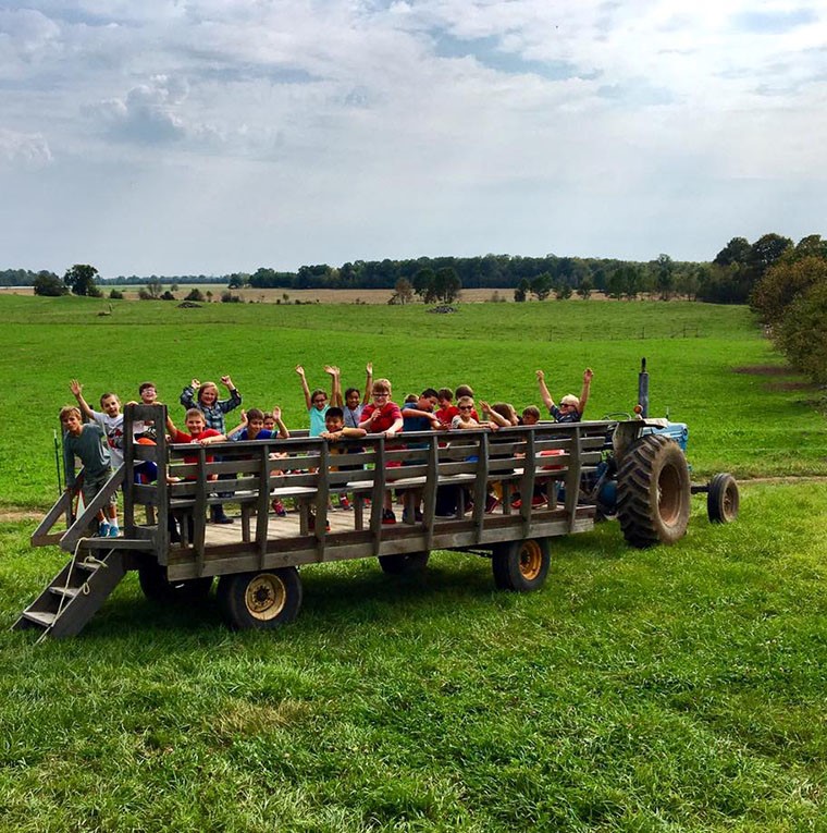 People ride in a wagon tractor trailer.