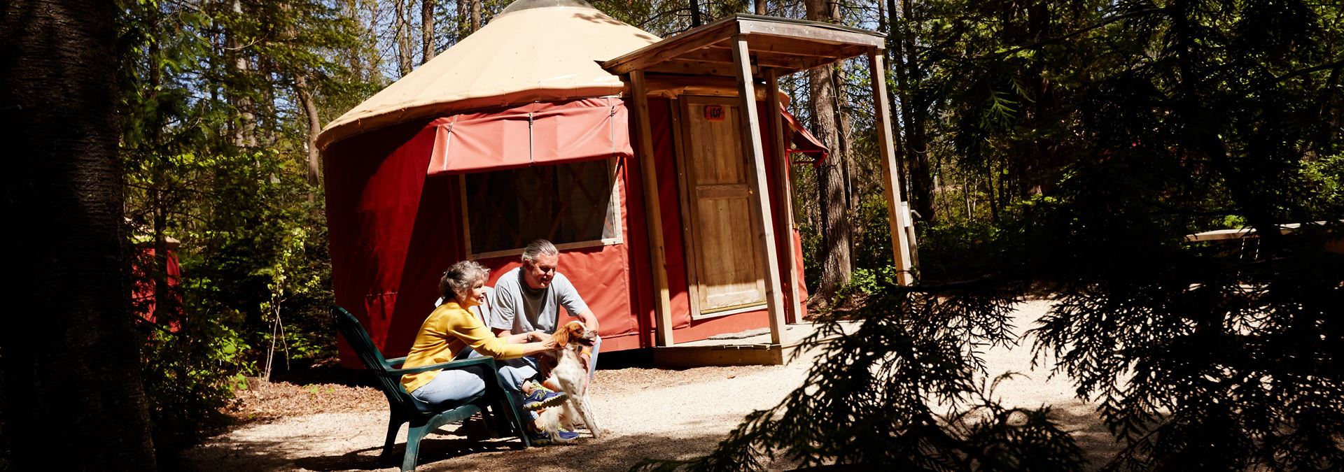 A couple and a dog sitting outside a large tent.