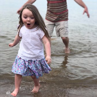 A little girl wading in the water at the lake.