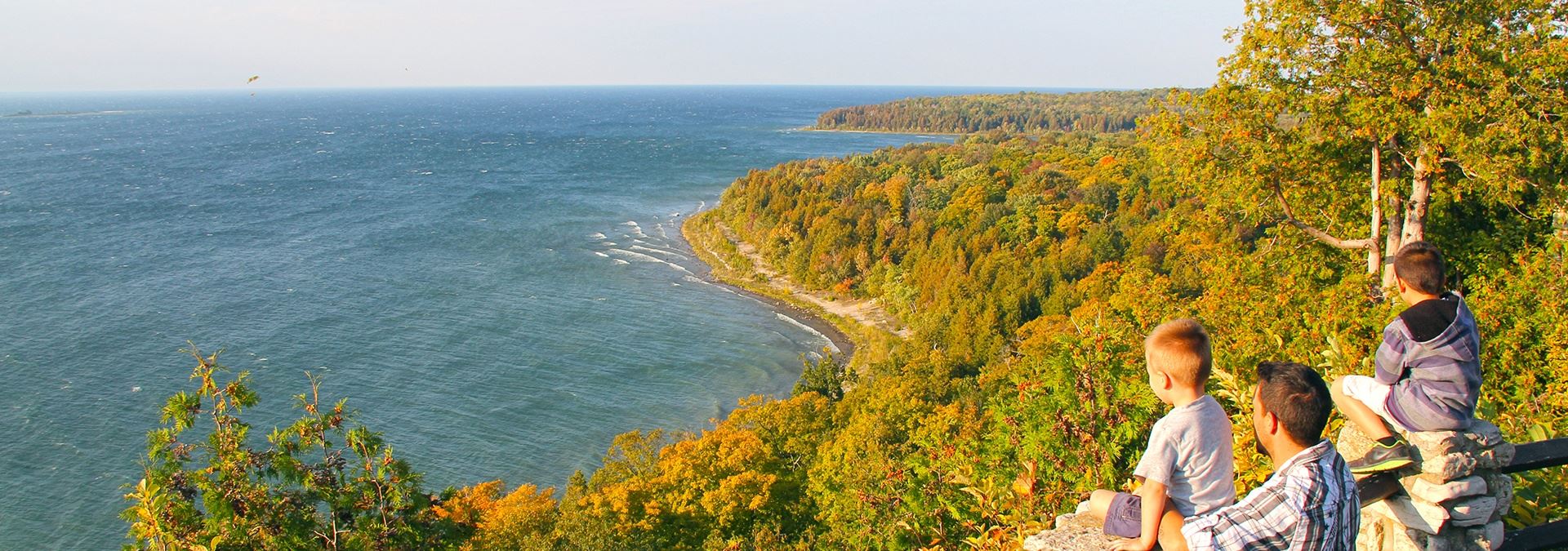 A family looking out over the trees and lake from a bluff.