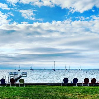 Bright blue sky with clouds over the lake with sailboats out on the water