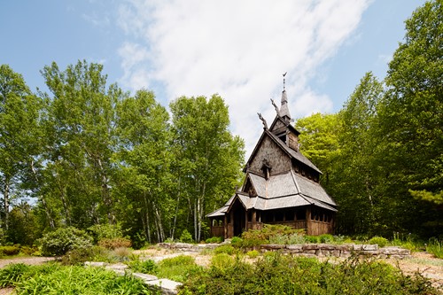 The grand Stavkirke church in a clearing surrounded by trees.
