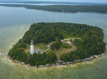 A white lighthouse on a tree-covered island.