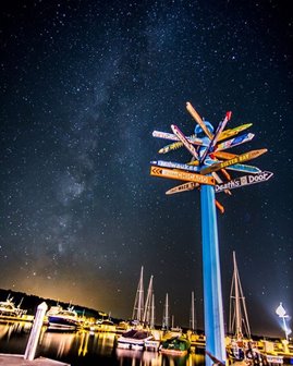 A signpost with signs pointing in all directions at night