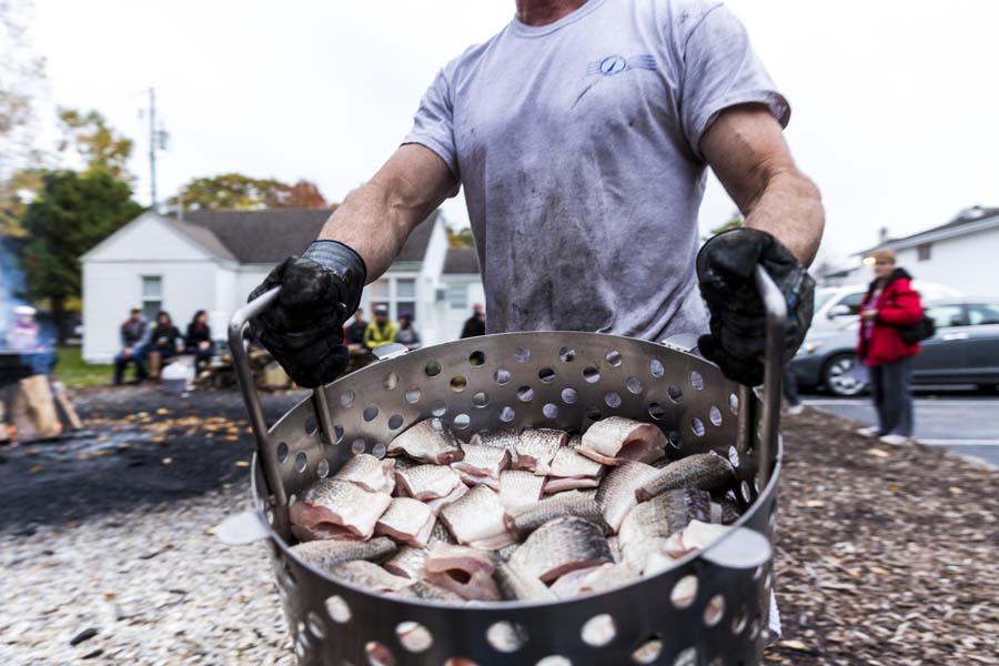 A boilmaster shows off a bucket of fresh-caught fish.