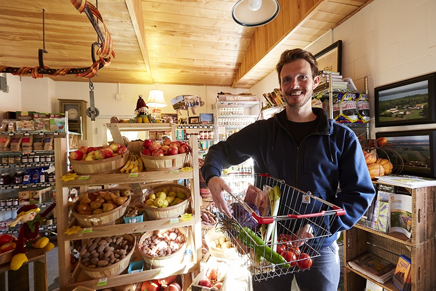 A farmer stands proudly among his produce in a market shop.