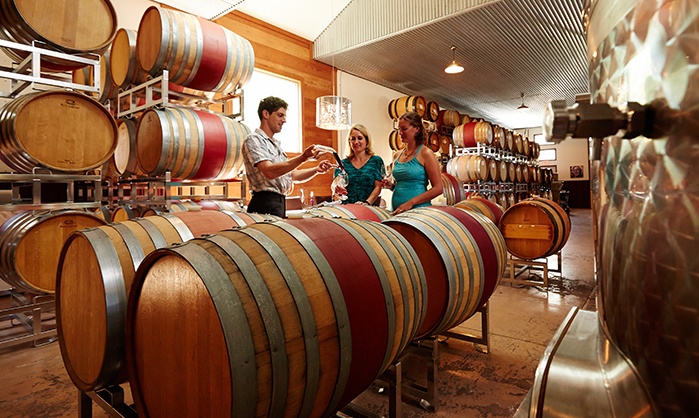 Friends take a wine tour among barrels and wine bottles at a Door County winery.