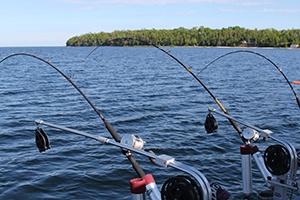 Two fishing rods in holders on the side of a boat.