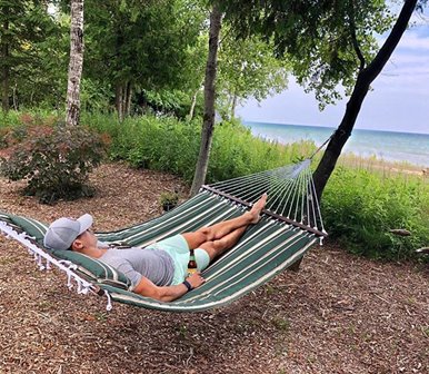 A woman hammocking near trees and the water