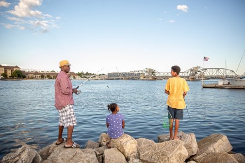 A family fishing off of the rocks.