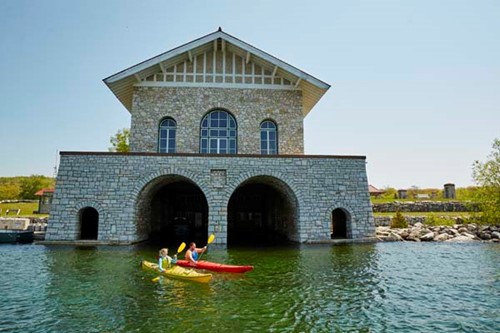 A couple kayaks in front of the majestic stone Thordarson Boathouse on Rock Island.