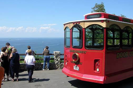 A red trolly parked in front of an area overlooking the lake.