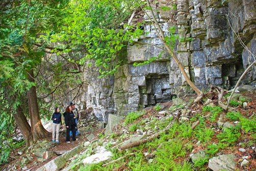 A group of people hiking below stone cliffs.