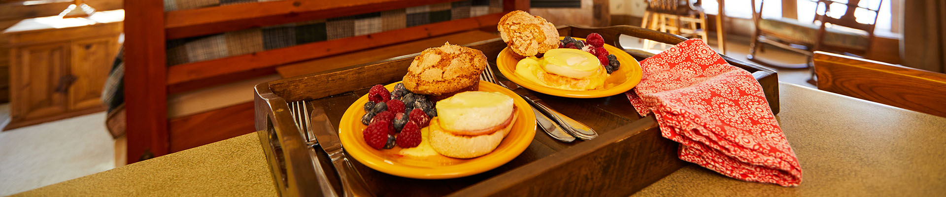 A couple chats in bed with a beautiful breakfast spread laid out before them on a tray.