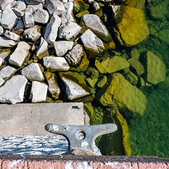 Looking down at large rocks on the shoreline with half of them submerged in the water