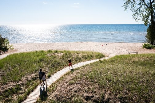 People walking a wooden path to the beach.