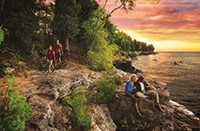 Hikers and a couple watching the sunrise at Cave Point County Park.